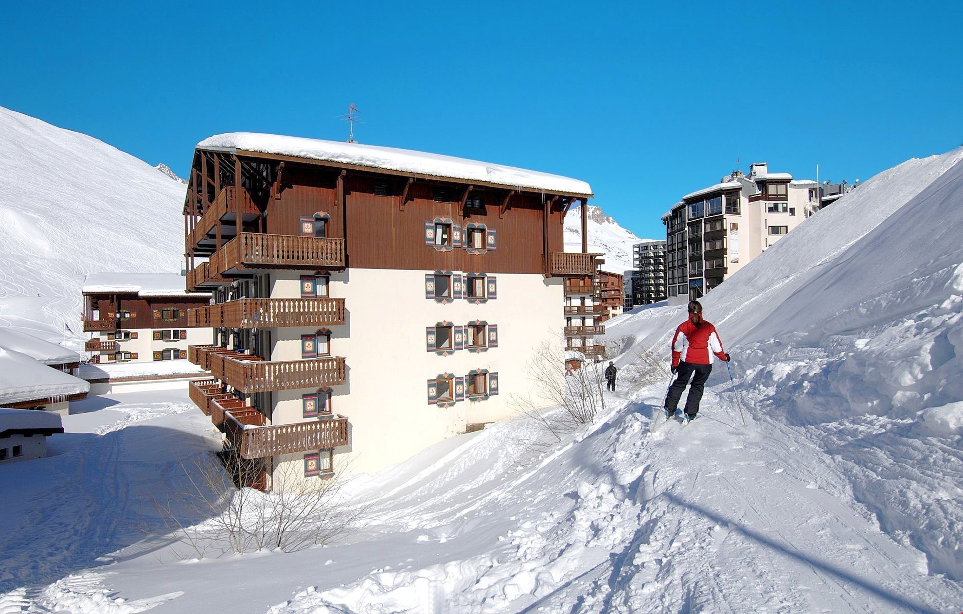 A multi-story wooden building with balconies, surrounded by snow-covered slopes.