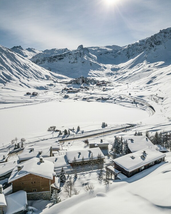 Ein verschneites Bergdorf mit Häusern und Skipisten.