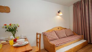 Una habitación acogedora con una cama de madera, una mesa de comedor con alimentos para el desayuno y una lámpara fijada a la pared.