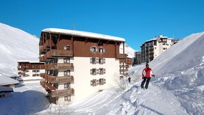 Un edificio de madera de varios pisos con balcones, rodeado de laderas nevadas.