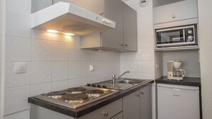Una cocina compacta con estufa a gas, microondas y cafetera.