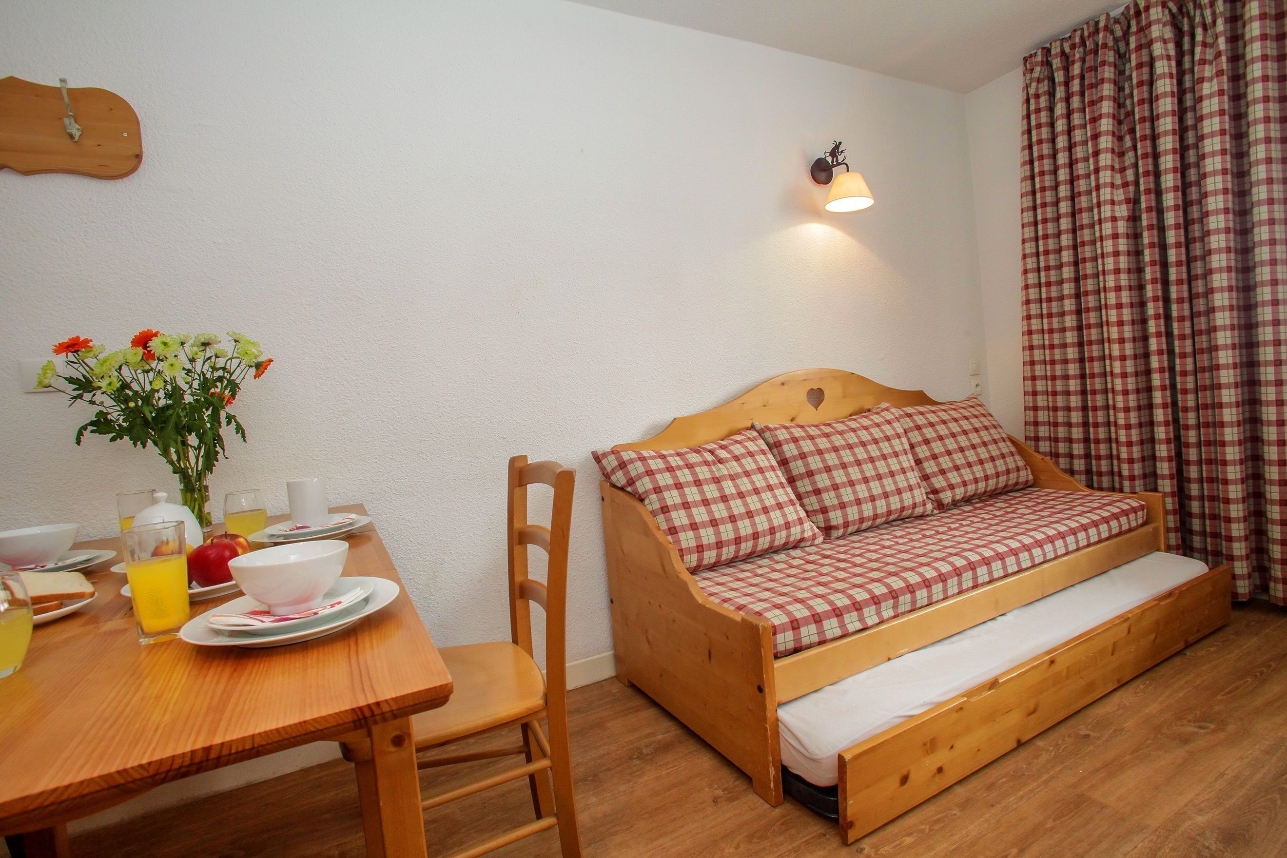 A cozy room with a wooden bed, a dining table with breakfast items, and a wall-mounted light fixture.
