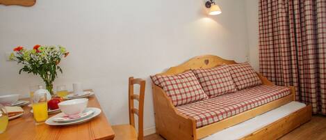 A cozy room with a wooden bed, a dining table with breakfast items, and a wall-mounted light fixture.