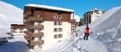 A multi-story wooden building with balconies, surrounded by snow-covered slopes.