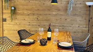 A wooden dining table with a bottle of wine, glasses, and a small decorative item. - SnowKaya Appartement/Fewo 5-Bettwohnung by Interhome (Engelberg)