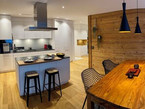 A modern kitchen with a central island, bar stools, and a dining table with chairs. - SnowKaya Appartement/Fewo 5-Bettwohnung by Interhome (Engelberg)