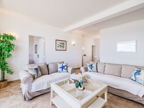 Uma sala de estar moderna com dois sofás, uma mesa de centro de vidro e um vaso com planta.
