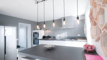 Een koelkast, een vaatwasser, kookgerei, borden en bestek, eettafels