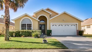 A two-story house with a garage, a front entrance, and a well-maintained lawn. - PRIVATE Pool, 3mi to Disney, Forest view with total privacy, Game room (Kissimmee)