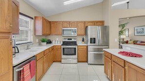 A modern kitchen with wooden cabinets, stainless steel appliances, and a white countertop. - PRIVATE Pool, 3mi to Disney, Forest view with total privacy, Game room (Kissimmee)