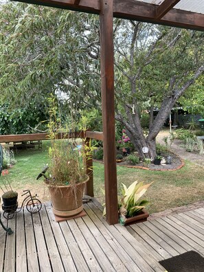 A wooden deck with potted plants and a pergola structure. - Much Loved Period Cottage (Penguin)