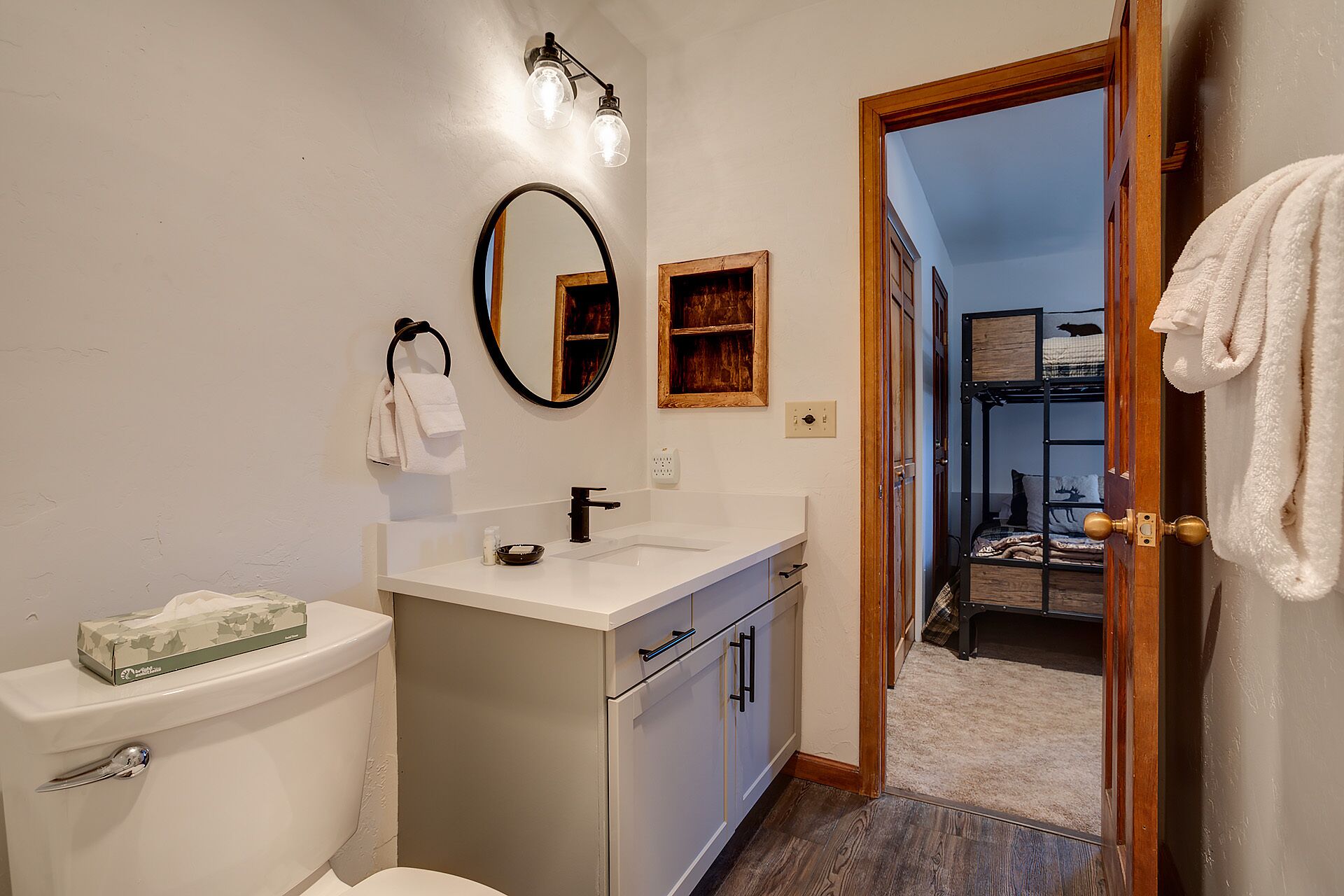 A bathroom with a toilet, sink, mirror, and towel rack.