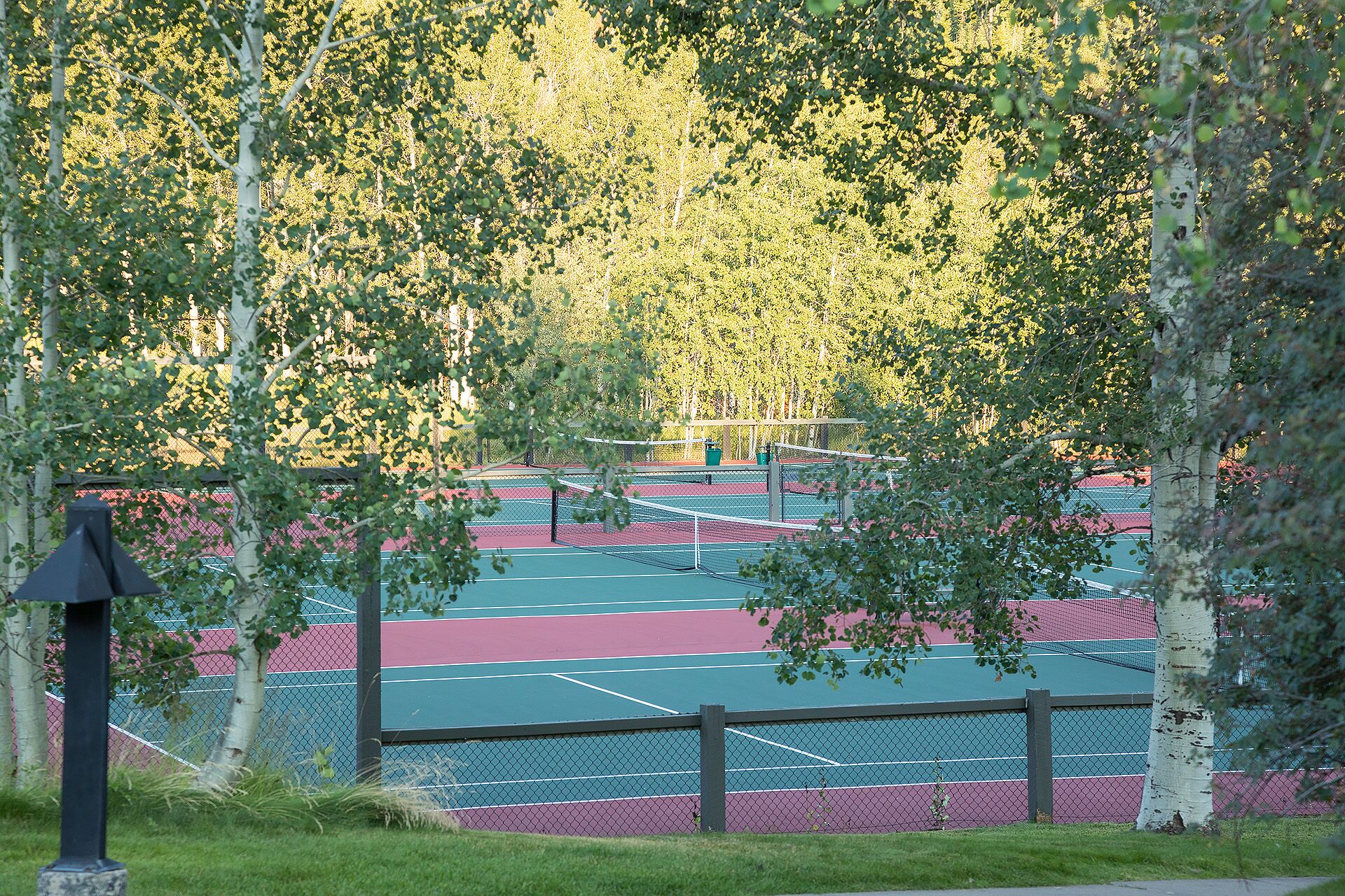 Un campo da tennis all'aperto circondato da alberi.