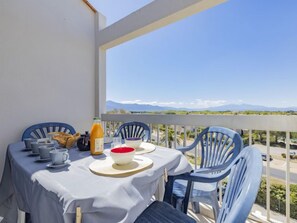 Ein Balkon mit einem Tisch, gedeckt für ein Frühstück, inklusive Croissants, Kaffeetassen und einer Orangensaftflasche.