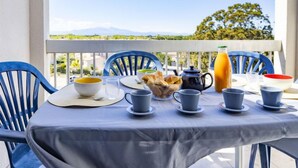 A balcony table set with breakfast items, including croissants, a teapot, and a bottle of orange juice. - Les Frégates by Interhome (Saint Cyprien)