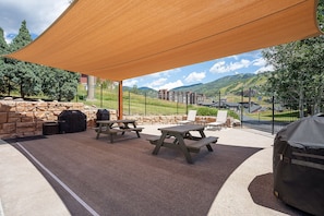 Enjoy al fresco dining with a mountain view from this patio, featuring a picnic table, chairs, barbecue grill, and covered grill.
