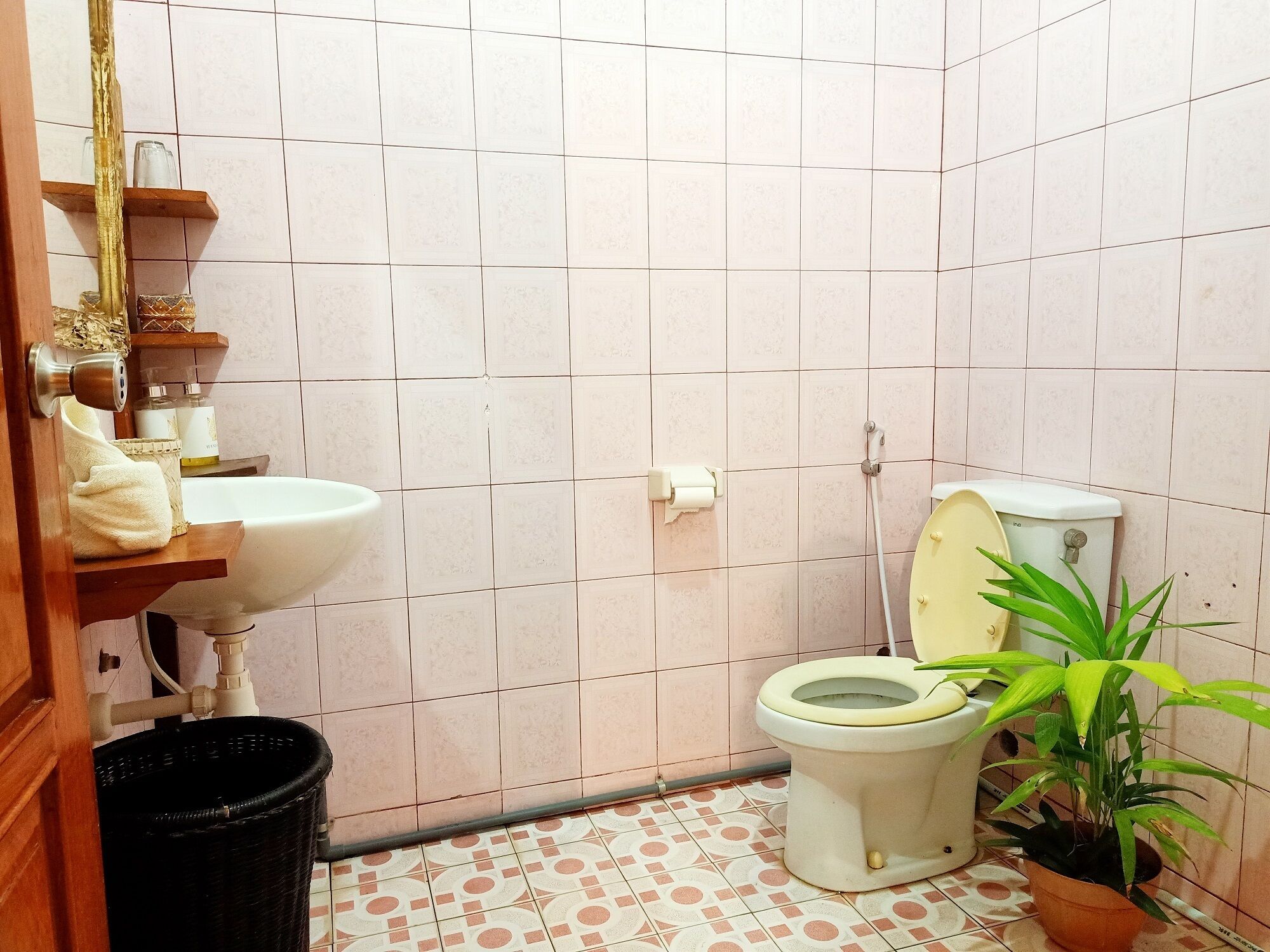 Ein kleines Badezimmer mit Toilette, Waschbecken und einer Topfpflanze.