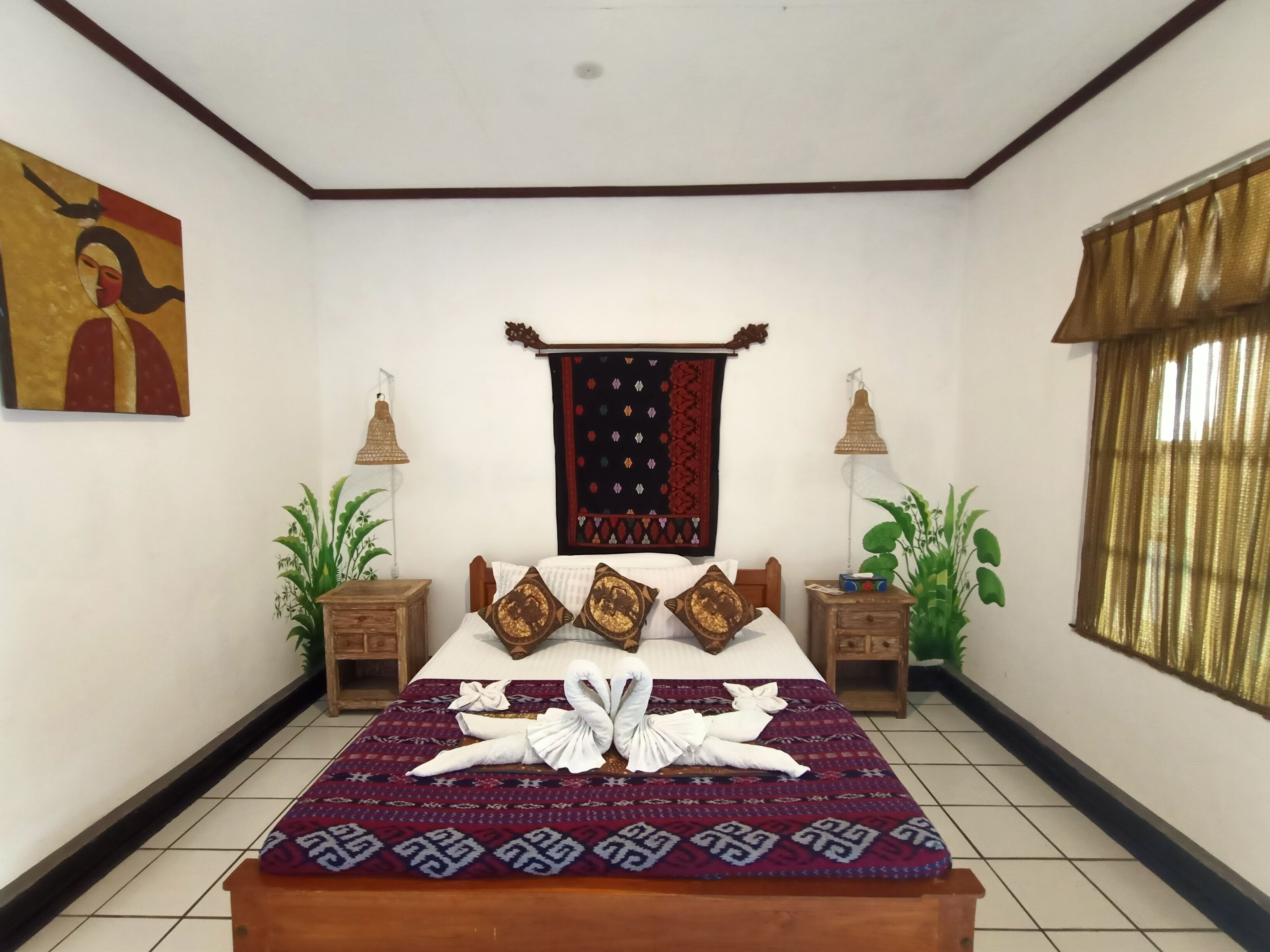 A neatly arranged bedroom with a bed, two nightstands, a wall hanging, and a window with curtains.