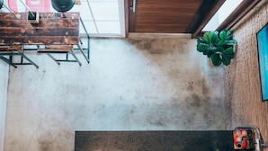 Een modern interieur met een houten bankje, een plant in pot en een betegelde vloer.
