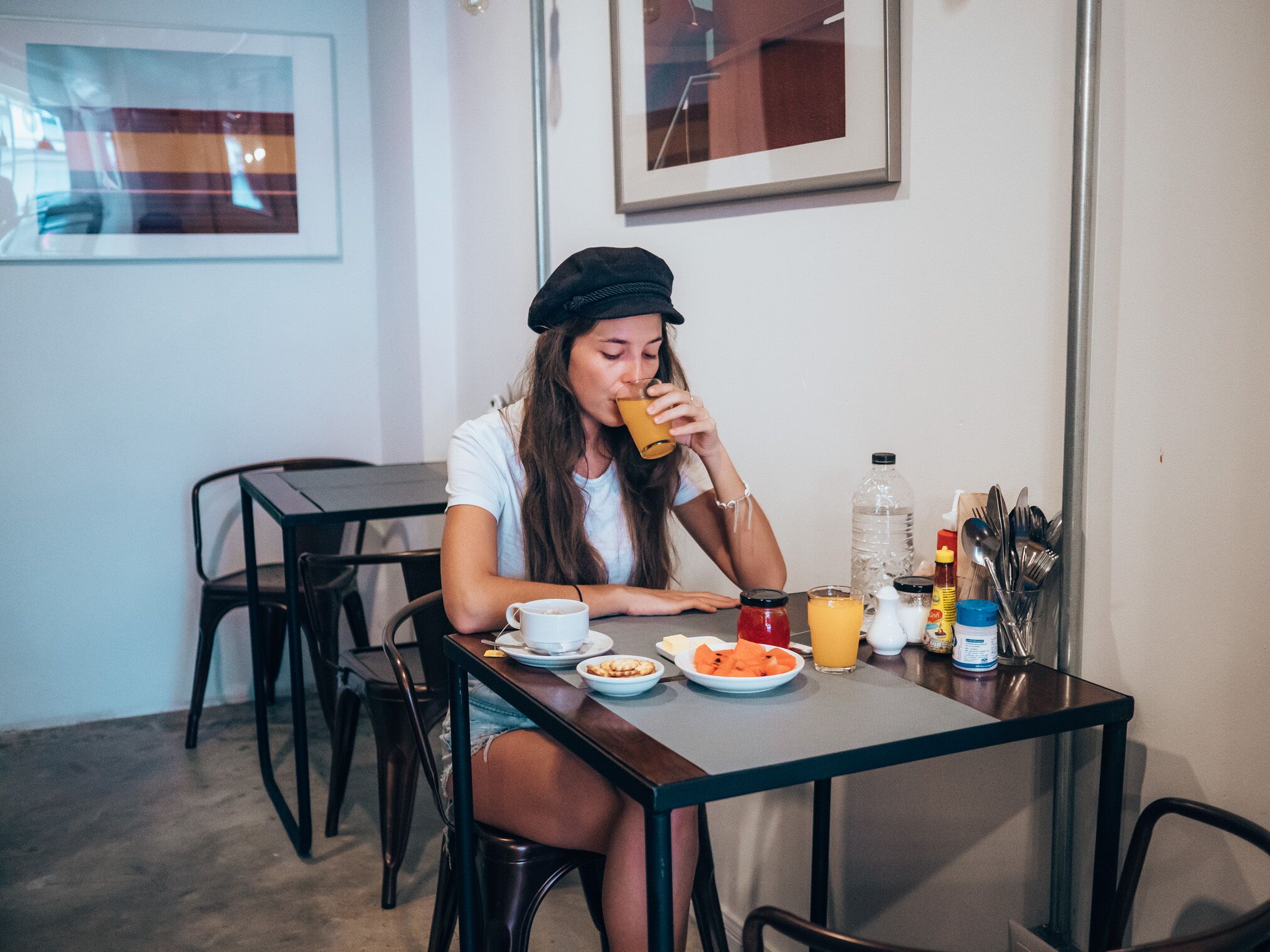A person sitting at a table with a meal, a water bottle, and condiments.