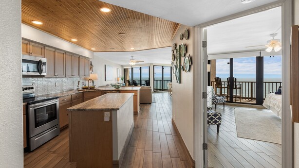 Una cocina moderna con armarios de madera, una isla central y vistas a un balcón con mobiliario exterior.