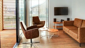 A modern living room with a sofa, two armchairs, a coffee table, and a TV. - Oesterdam Resort by Interhome (Tholen)