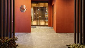 A modern building entrance with a tiled pathway, a metal gate, and a logo on the wall.