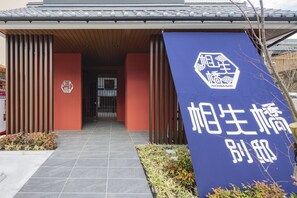 A building entrance with a blue banner displaying a logo and Japanese text. - Aioibashi Bettei (Imari)