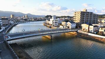 A river with a bridge, buildings, and mountains in the background.