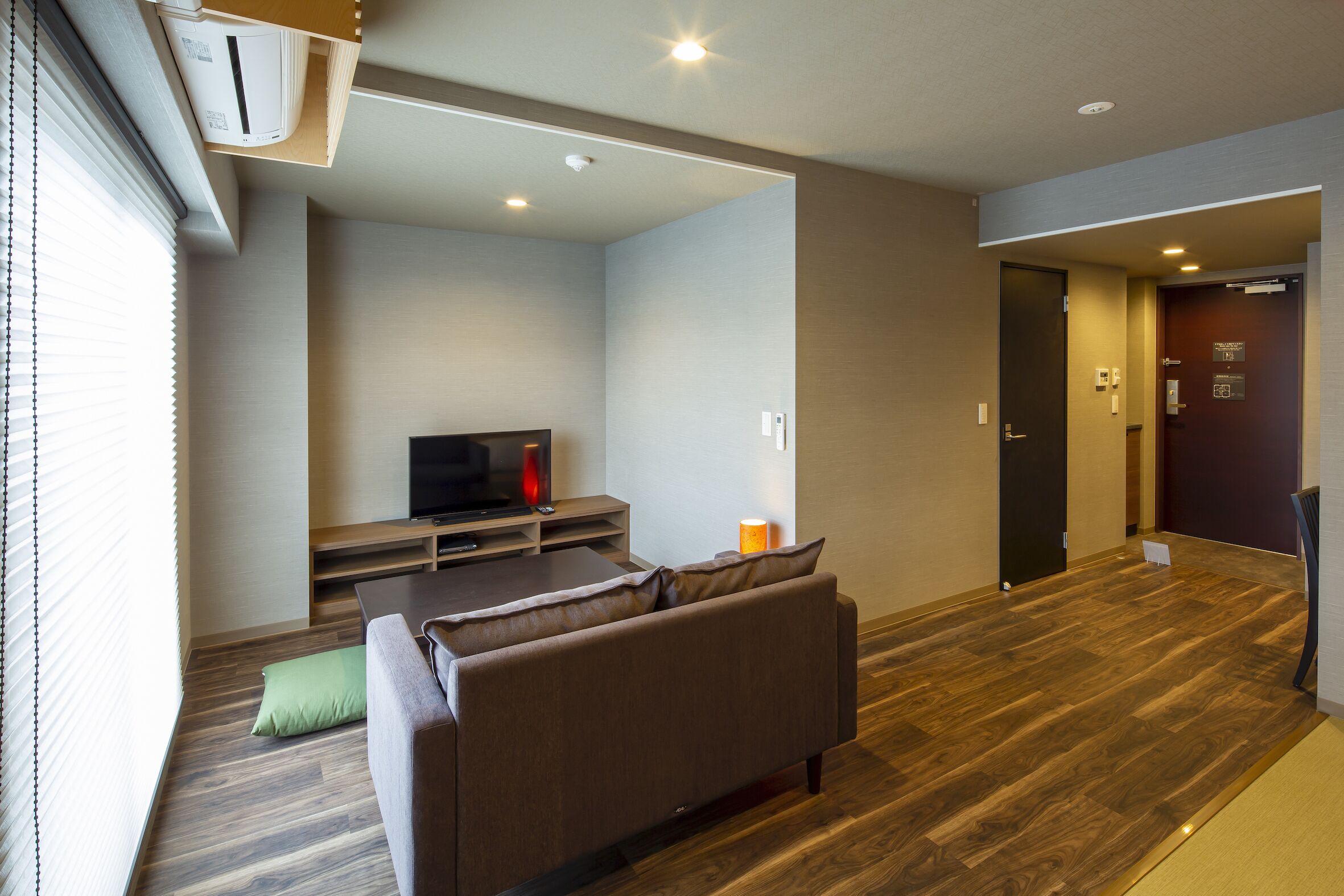 A modern living room with a sofa, TV, and wooden flooring.