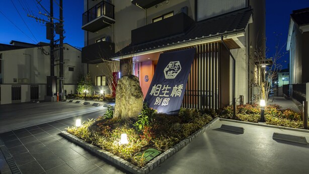 A building with a signboard, a stone monument, and a well-lit entrance.