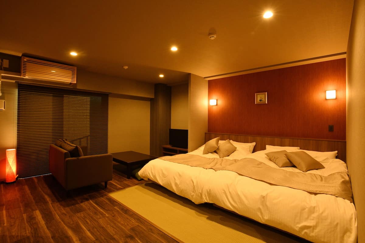 A modern hotel room with a large bed, a seating area, and a television.