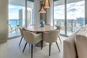 Enjoy meals with a view of the city skyline and ocean from this dining area with a round table and four chairs.