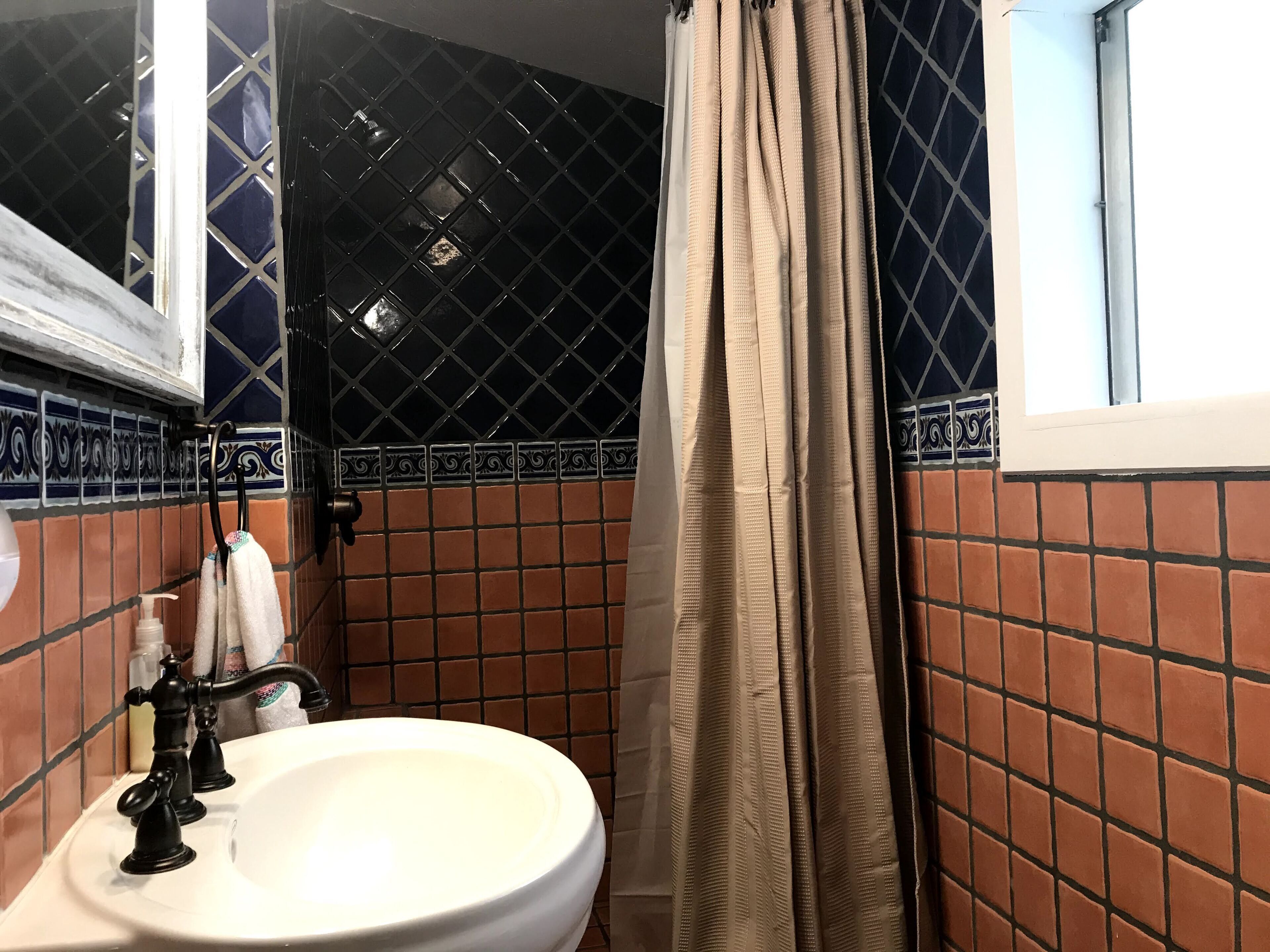 A bathroom with a white sink, black faucets, and a beige shower curtain.