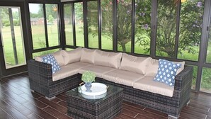 A covered patio area with a sectional sofa, a glass coffee table, and a view of a garden through large windows. - Beautiful Rustic Murfreesboro Home just minutes from I24, MTSU and more (Murfreesboro)