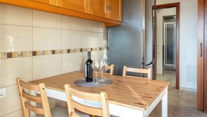 Una cocina con armarios de madera, salpicadero de azulejos y una mesa de comedor con sillas.
