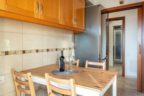 A kitchen with wooden cabinets, a tiled backsplash, and a dining table with chairs. - Skyline Blue Dream (Faro)