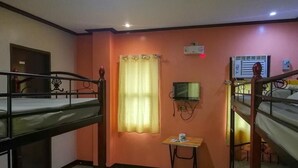 A dormitory room with bunk beds, a small table, a television, and an air conditioning unit. - ROEXCIN Tourist Inn (Claver)