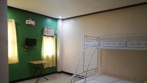 A bunk bed room with a green wall, a small table, a TV, and an air conditioning unit. - ROEXCIN Tourist Inn (Claver)