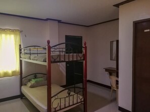 A room with bunk beds, a small table, and a door.