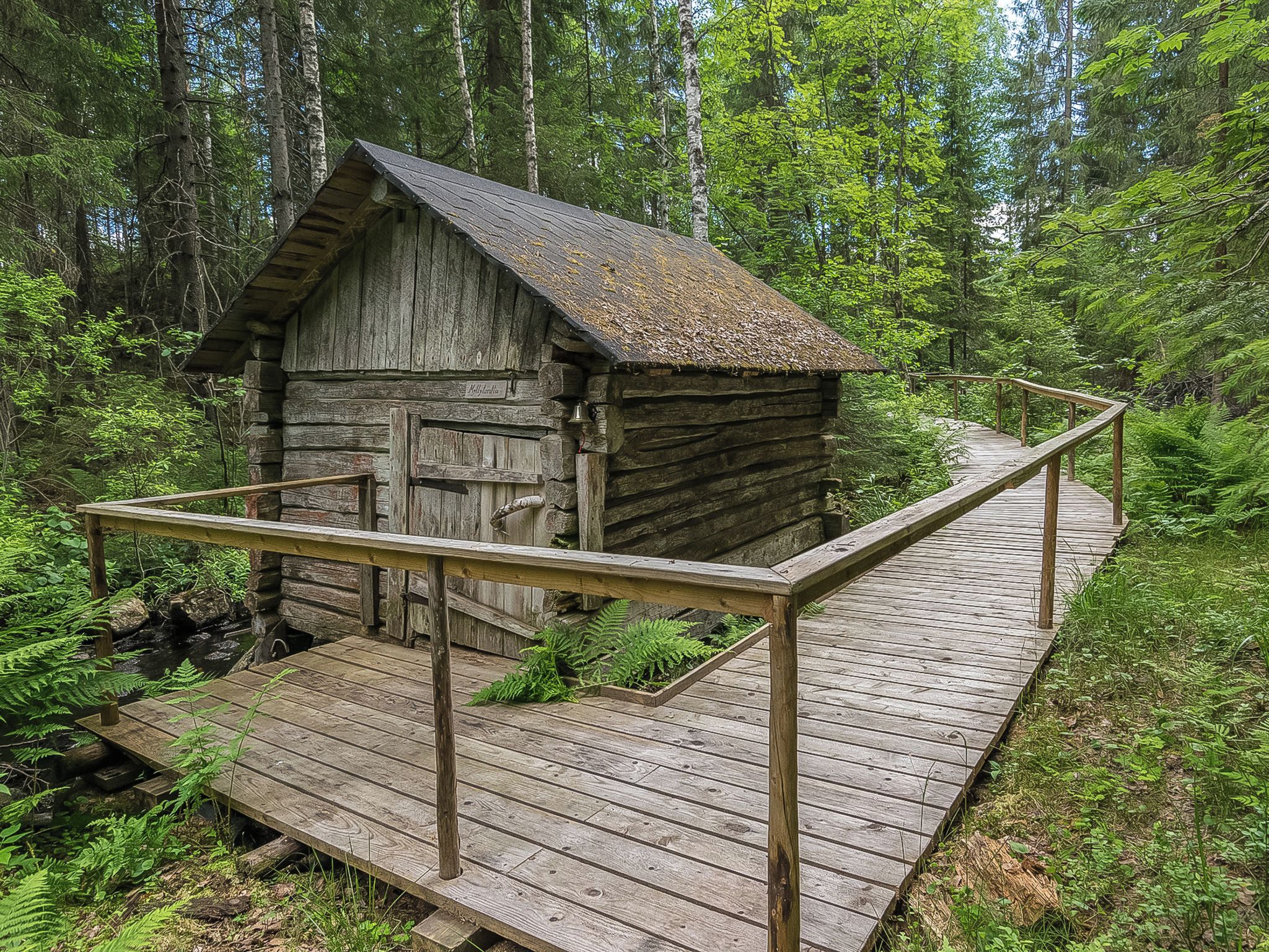 Une cabane rustique dotée d’une terrasse en bois et d’une rambarde en métal.