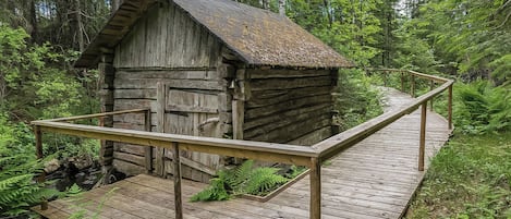 A rustic cabin with a wooden deck and a metal railing.