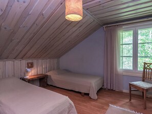 A bedroom with two beds, a desk with a lamp, a chair, and a window with curtains. - Myllytupa by Interhome (Pieksämäki)