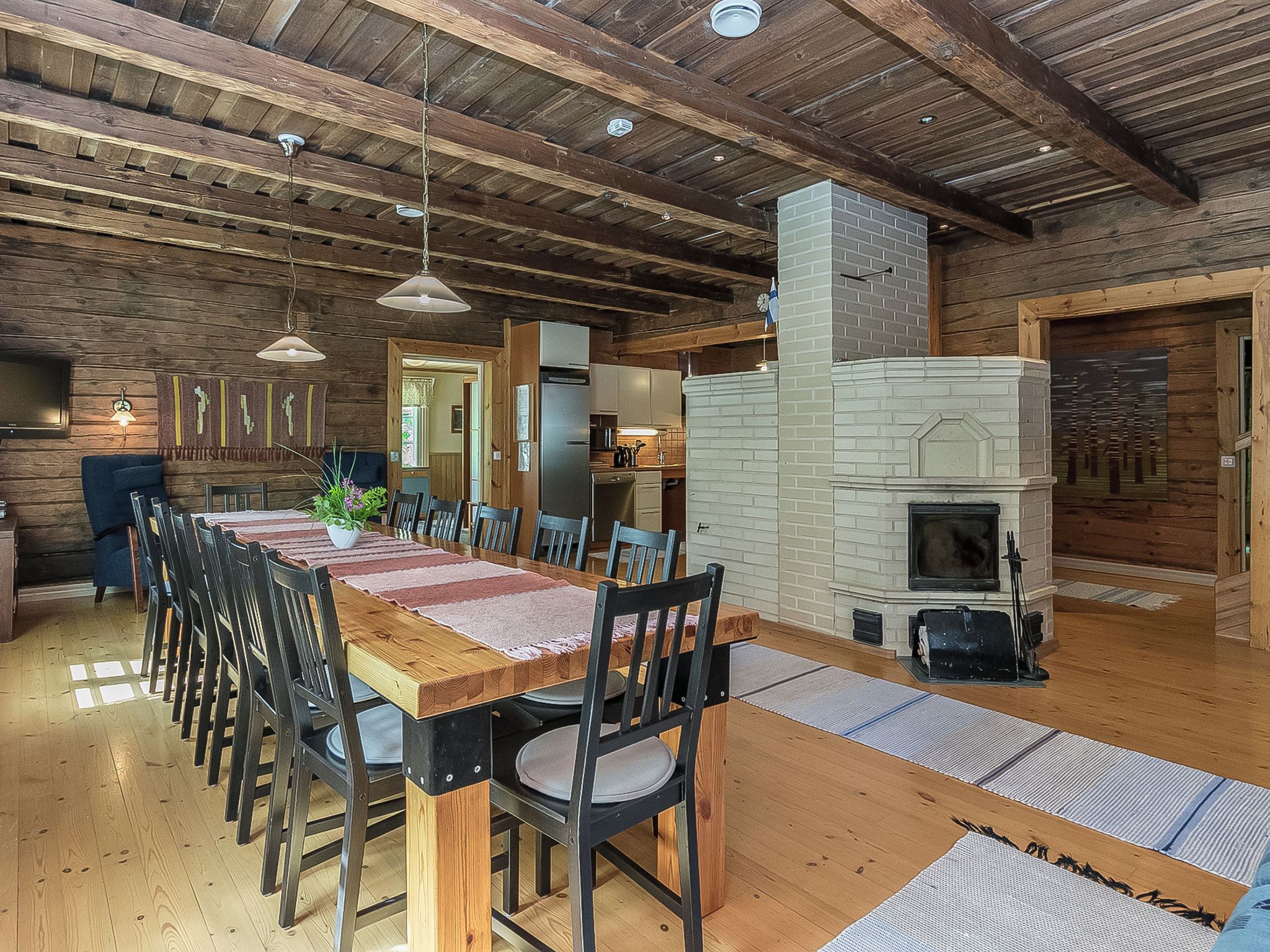 Un coin repas rustique avec une longue table en bois, des chaises et une cheminée.