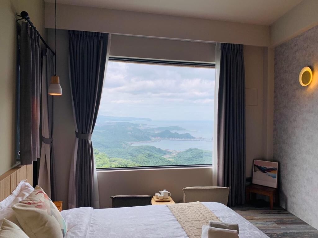 A hotel room with a large window offering a scenic view of a mountainous landscape.