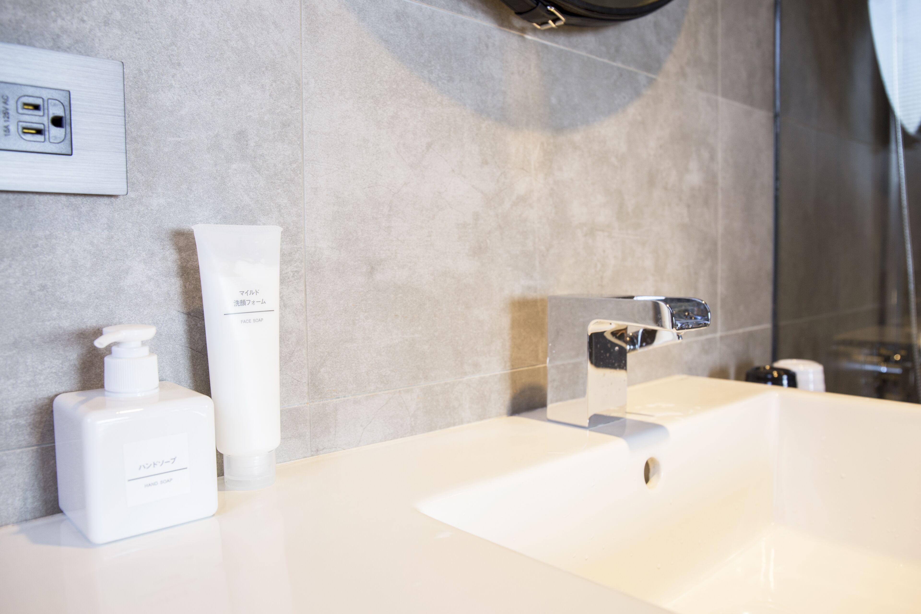 A bathroom with a white sink, a mirror, and two white bottles on the counter.