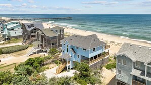 Una zona residencial costera con propiedades frente al mar, incluyendo casas con balcones y un muelle que se adentra en el océano.