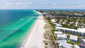 An aerial view of a coastal area with a beach, a marina, and a resort with multiple buildings and a swimming pool. - ⚓5400 Gulf Dr! 55+ condo with amazing pool just steps away from the beach!⚓🏖 (Holmes Beach)