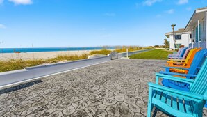 A beachside patio with colorful Adirondack chairs and a view of the ocean. - ⚓5400 Gulf Dr! 55+ condo with amazing pool just steps away from the beach!⚓🏖 (Holmes Beach)