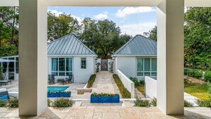 Et moderne hus med en midtersti, der fører til en hoveddør, omgivet af en velplejet have og en swimmingpool.